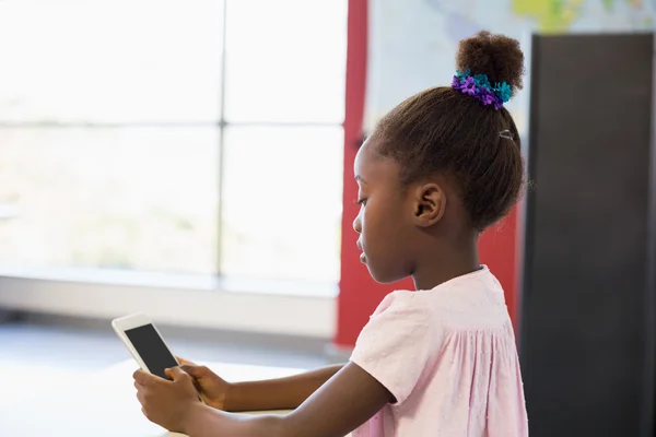 Schoolmeisje met behulp van de telefoon in de klas — Stockfoto