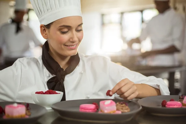 Vrouwelijke chef-kok afwerking dessert platen — Stockfoto