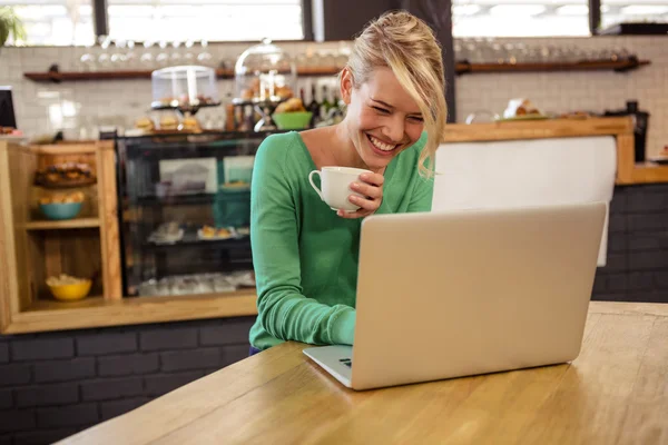 Kobieta pije kawę i korzysta z laptopa — Zdjęcie stockowe