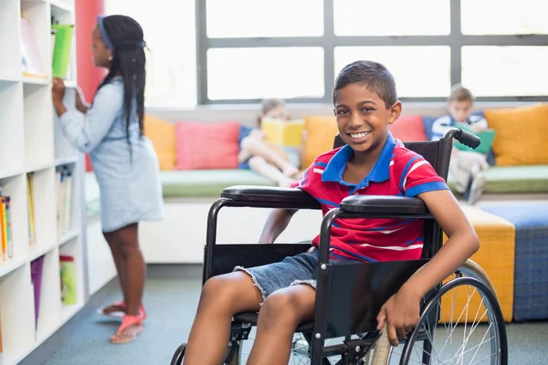 Studente disabile sulla sedia a rotelle in biblioteca — Foto Stock