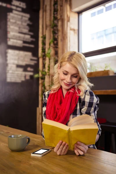 Woman reading novel in cafeteria — Stock Photo, Image