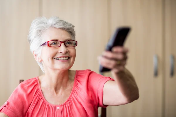 Senior mulher usando um controle remoto — Fotografia de Stock