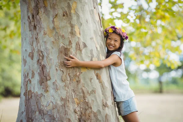 Menina abraçando árvore tronco no parque — Fotografia de Stock