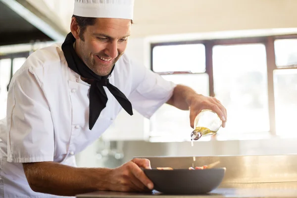 Шеф-повар наливает оливковое масло на еду — стоковое фото