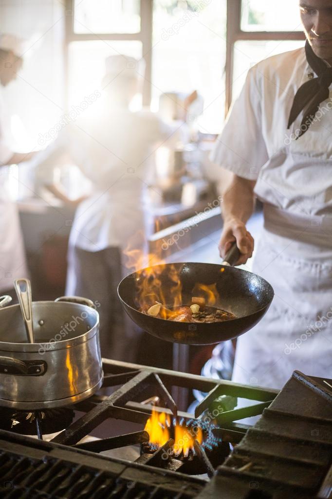 Chef cooking in kitchen stove Stock Photo by ©Wavebreakmedia 112897276