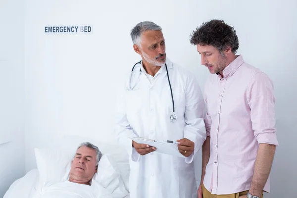 Médico masculino discutindo relatório médico com o homem — Fotografia de Stock