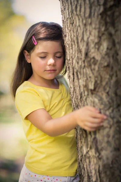Thoughtful girl leaning on tree trunk — Stock Photo, Image