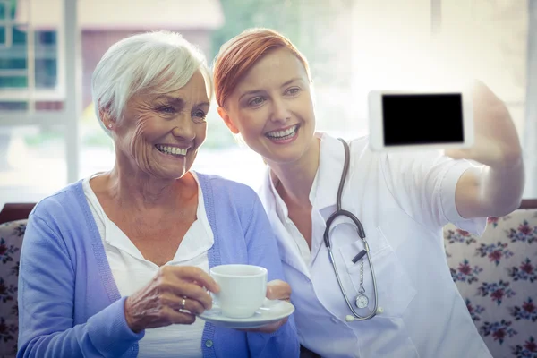 Médico y paciente mirando el teléfono mientras toma el té —  Fotos de Stock