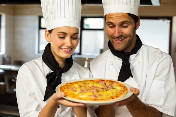 Dos chef jefe presentando una pizza —  Fotos de Stock