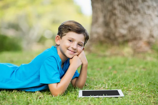 Jongen liggend op gras met tablet — Stockfoto