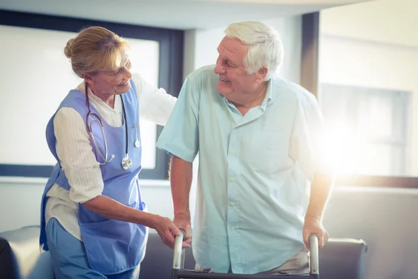 Vrouwelijke arts helpen senior man om te wandelen met walker — Stockfoto