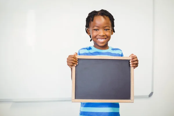 Skolan pojke håller skiffer i klassrummet — Stockfoto