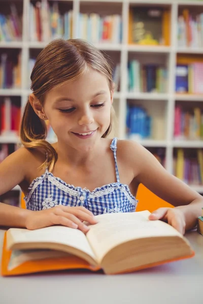 Chica de la escuela leyendo un libro en la biblioteca — Foto de Stock