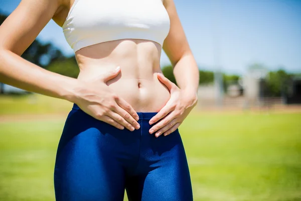Mid-section of female athlete touching her belly — Stock Photo, Image