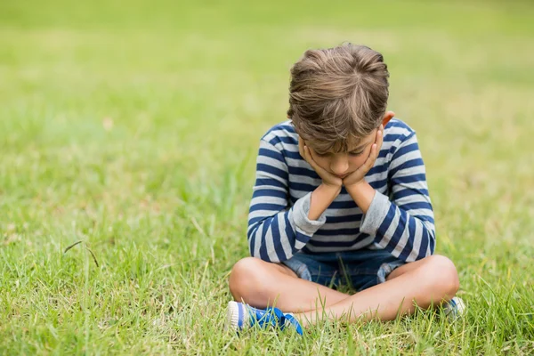 Rozrušený chlapec seděl na trávě — Stock fotografie