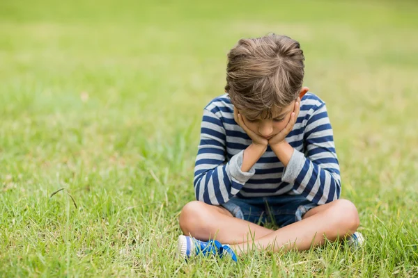 Garçon bouleversé assis sur l'herbe — Photo