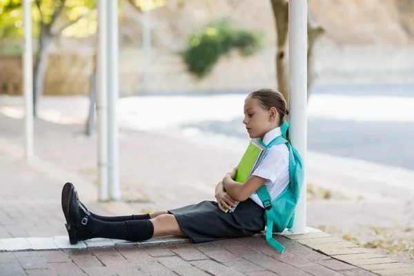 Doordachte schoolmeisje zit in gang — Stockfoto