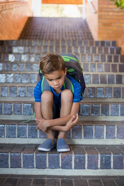 Sorgliga skolpojke sitter på trappan — Stockfoto