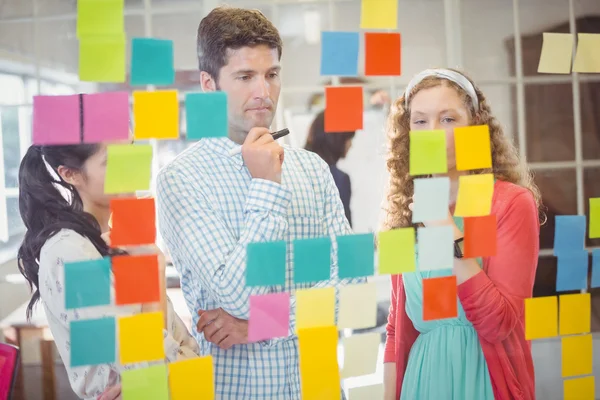 Colegas mirando notas pegajosas en la pared — Foto de Stock