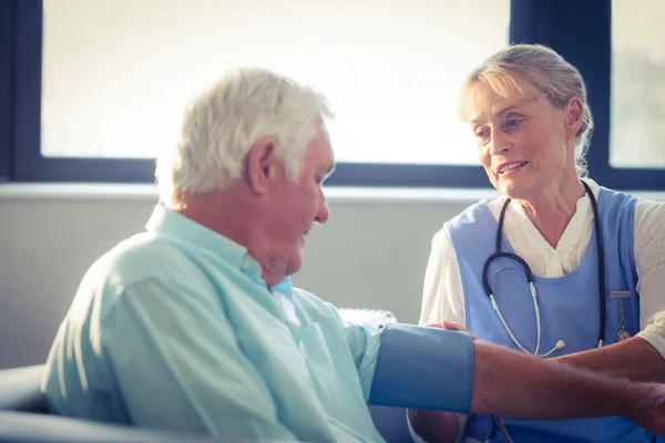 Vrouwelijke arts controleren bloeddruk van senior man — Stockfoto