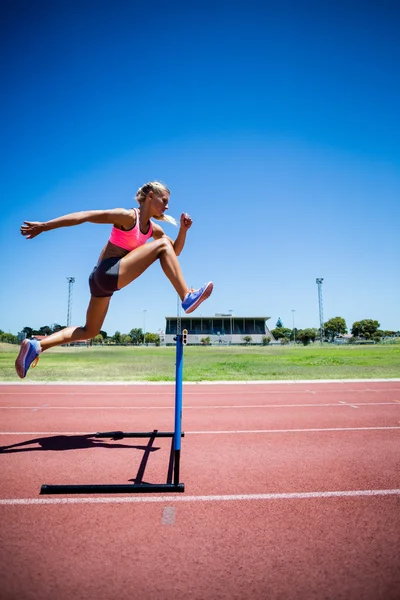 Atleta feminina pulando acima do obstáculo — Fotografia de Stock