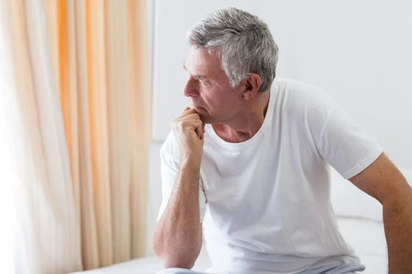 Preoccupato uomo anziano seduto sul letto — Foto Stock