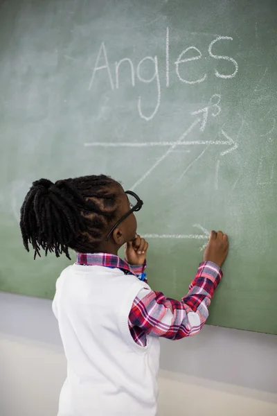 Schoolmeisje doen wiskunde op schoolbord — Stockfoto