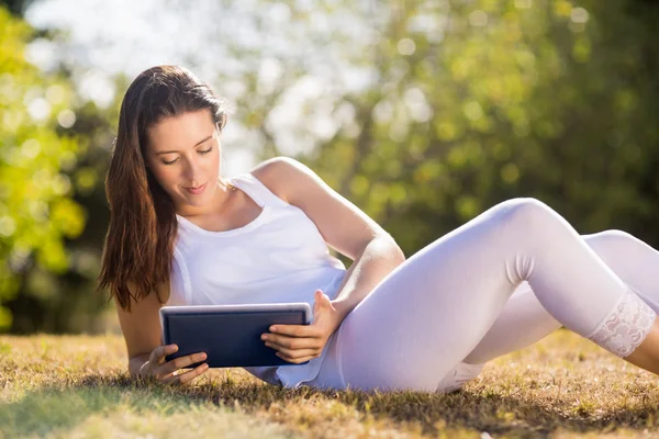 Frau sitzt auf Gras und nutzt digitales Tablet — Stockfoto