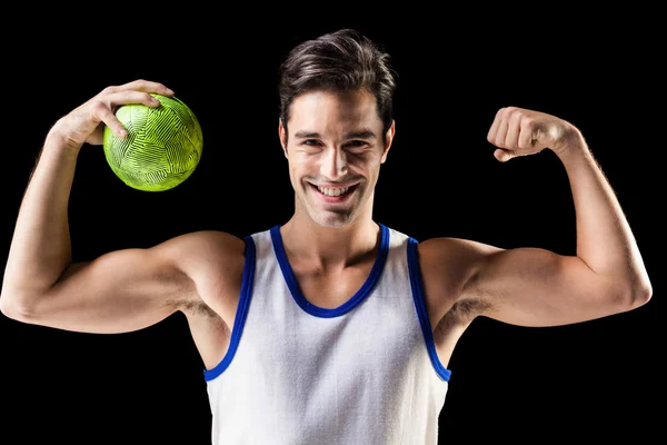 Retrato de homem atleta feliz segurando bola e mostrando músculos — Fotografia de Stock