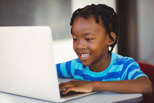 Leende skolpojke med laptop i klassrummet — Stockfoto