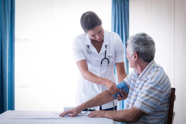 Médico femenino que revisa la presión arterial del hombre mayor —  Fotos de Stock