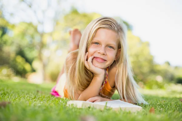 Молодая девушка лежит на траве с книгой — стоковое фото