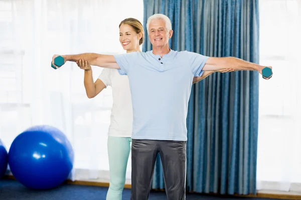 Instructor helping senior man with weights — Stock Photo, Image