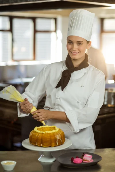 Fêmea chef piping glacê no bolo — Fotografia de Stock