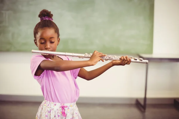 Skolflicka spelar flöjt i klassrummet — Stockfoto
