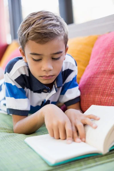 Schoolboy on sofa and reading book — Stock Photo, Image