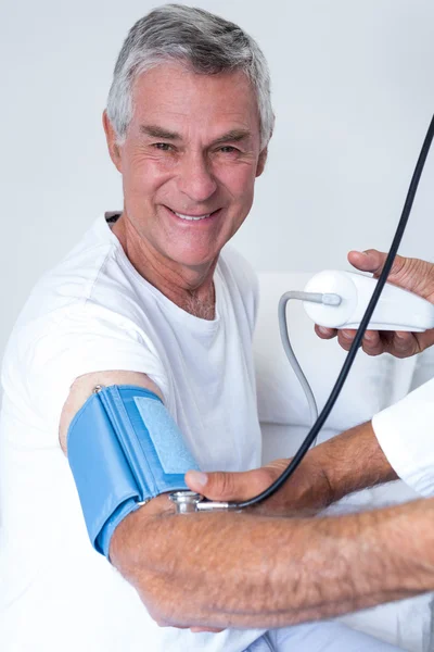 Doctor checking senior mans blood pressure — Stock Photo, Image