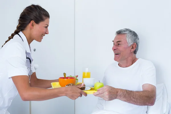 Doctora sirviendo el desayuno a un hombre mayor —  Fotos de Stock