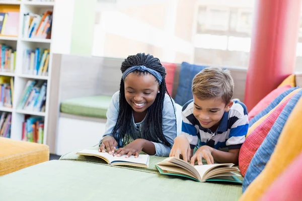 Los niños de la escuela en sofá y libro de lectura — Foto de Stock