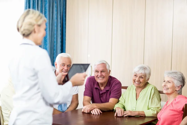 Seniors listening to nurse with tablet — Stock Photo, Image