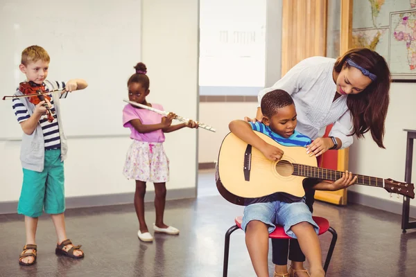 Leraar helpen kinderen om te spelen muziekinstrument — Stockfoto