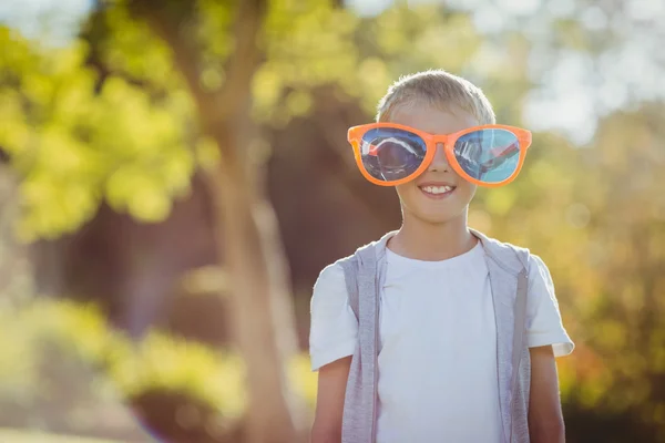 Jongen met gigantische zonnebril glimlachend op camera — Stockfoto