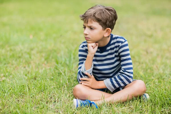Aufgebrachter Junge sitzt auf Gras — Stockfoto