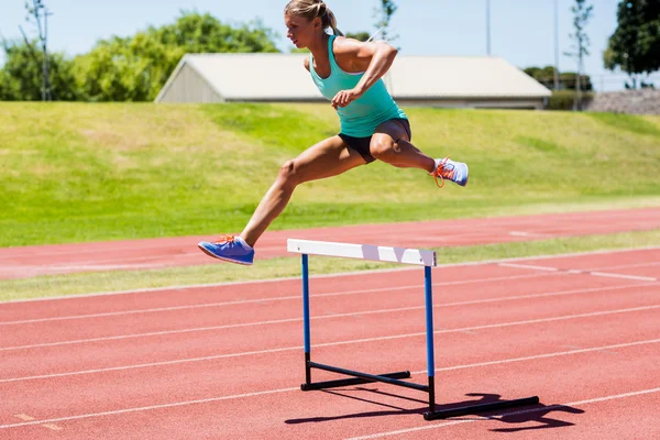Vrouwelijke atleet boven de hindernis springen — Stockfoto