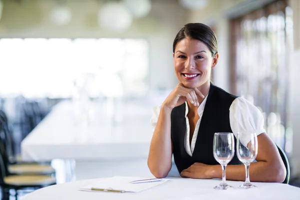 Uśmiechnięta kelnerka siedzi przy stole — Zdjęcie stockowe