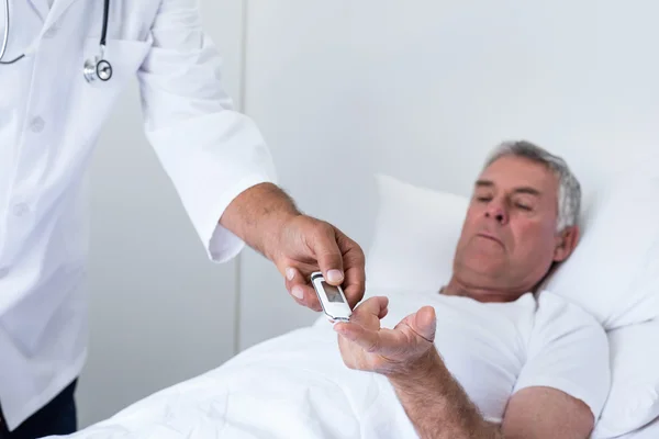 Male doctor testing diabetes of senior man — Stock Photo, Image