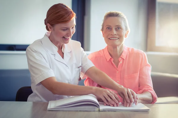Perawat wanita membantu pasien dalam membaca buku braille — Stok Foto