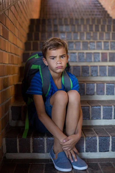 Sorgliga skolpojke sitter på trappan — Stockfoto