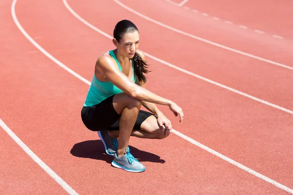 Atleta feminina ajoelhada na pista de corrida — Fotografia de Stock