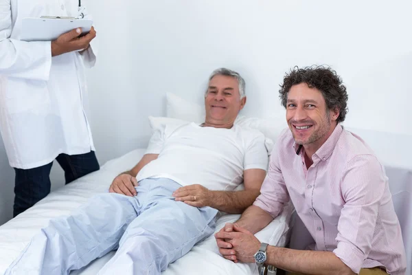 Человек сидит рядом с пациентом и улыбается — стоковое фото